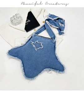 Détail du sac bandoulière en denim en forme d'étoile avec bords effilochés et sangle