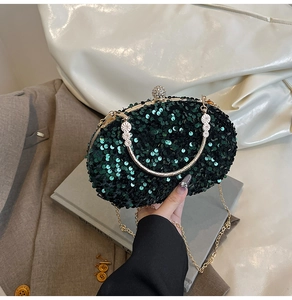 Detailed close-up of dark green sequin evening clutch bag with gold handle and diamond clasp