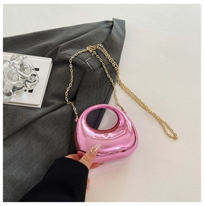 Close-up of a metallic pink dumpling-style crossbody bag with elegant gold chain strap