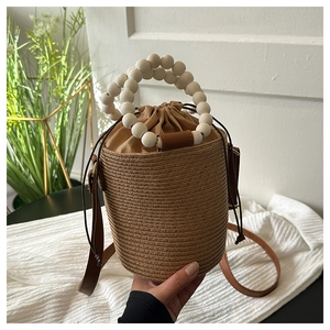 Detail of hand-woven straw bucket bag with wooden bead handle and drawstring closure