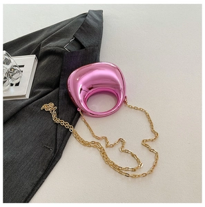 Macro detail of pink mirror acrylic bag with oval hollow handle and golden chain strap