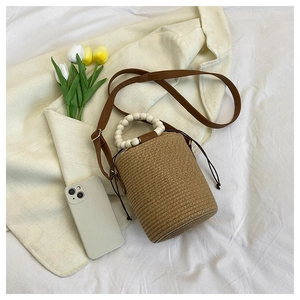 Detail view of woven bucket bag featuring wooden bead handles and drawstring closure