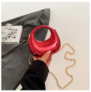 Macro detail of glossy metallic red crescent bag with gold chain and circular handle