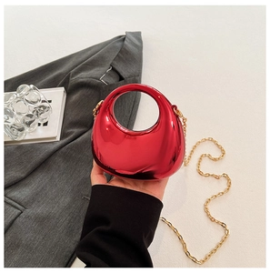 Close-up of bright red metallic acrylic mini bag with gold chain and circular handle