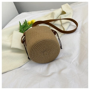 Detail of hand-woven straw bucket bag with wooden beads and drawstring closure