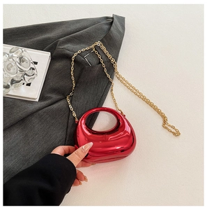Close-up of bright red metallic acrylic evening bag with gold chain and round handle