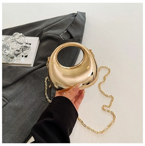 Detail of a gold metallic evening bag with a circular handle and detachable chain strap