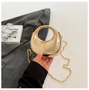 Close-up of a luxury gold mirror acrylic bag with a sleek round handle and chain strap
