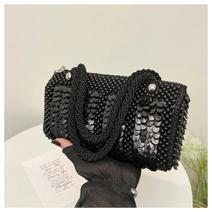 Detail of black beaded sequin handbag featuring thick woven handles and silver studs