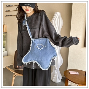 Détail d'un sac bandoulière étoile en denim bleu avec bords effilochés dans un café douillet