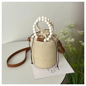 Detail of woven straw bucket bag with wooden bead handle and drawstring inner liner