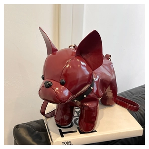Close-up of red patent leather puppy shaped crossbody bag with black rivet collar detail