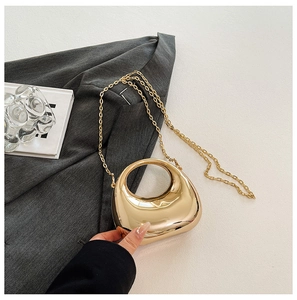 Macro view of golden acrylic clutch with high-gloss metallic finish and round handle