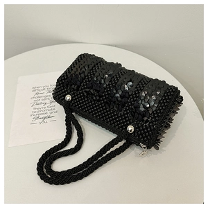 Detailed shot of black sequin pearl handbag with woven handle and metallic zipper