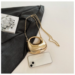 Close-up of golden acrylic mini clutch bag on dark blazer with chain strap detail