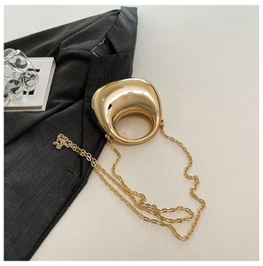 Detail of mini gold dumpling bag with metallic finish and delicate chain strap on blazer