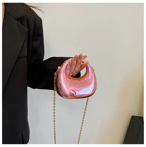 Close-up of metallic pink mirror mini crescent bag with gold chain strap on black blazer