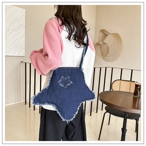 Détail d'un sac bandoulière en jean en forme d'étoile avec bords effilochés porté par un mannequin