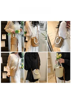 Detail of woven straw bucket bag with white pearl handle and brown leather shoulder strap