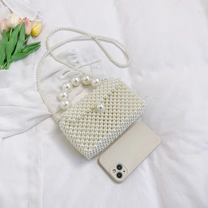 Mini sac à main en perles tressées avec grande anse et bandoulière sur tissu blanc