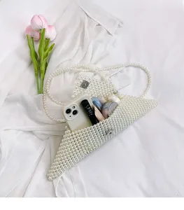 Detailed view of white pearl beaded envelope bag showing interior storage and silver magnetic clasp