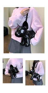 Close-up of French bulldog shaped crossbody bag in glossy black faux leather with strap