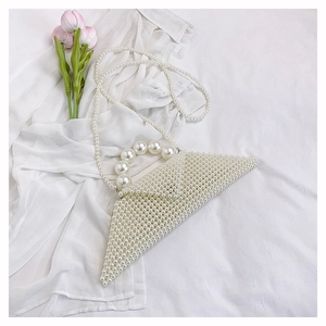 Detail of white pearl beaded handbag with large top handle and thin strap on a shirt