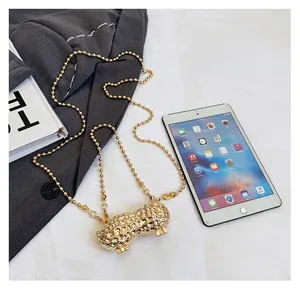 Detailed view of mini golden peanut shaped metal clutch bag next to iPad for size comparison