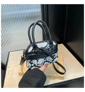 Dettaglio della mini borsa pitonata con cinturino a fibbia metallica e chiusura a zip