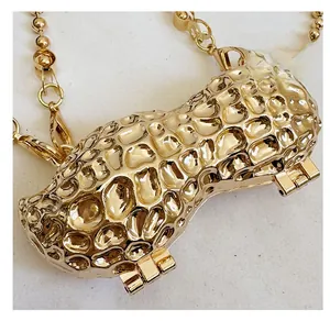 Detail of peanut-shaped gold metal mini bag with textured surface and bead chain strap