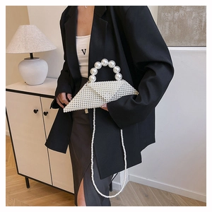 Detail of white pearl woven triangular handbag with circular handle and chain strap