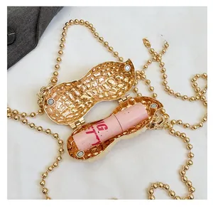 Close-up of golden peanut-shaped metal bag with pink lipstick inside and pearl chain