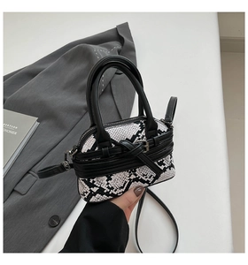Dettaglio della mini borsa a conchiglia con trama serpente bianca e nera e manici