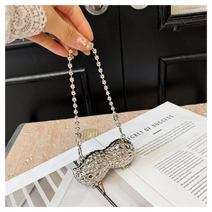 Close-up of a silver peanut-shaped metal mini bag with detailed shell texture and bead chain