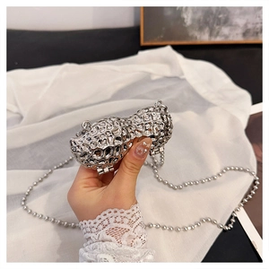 Close-up of peanut-shaped silver metal bag with detailed shell texture and bead chain