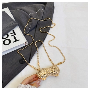 Macro shot of gold peanut shaped metal mini bag with textured finish and ball chain