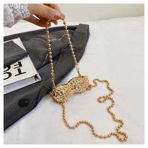 Detail of creative gold peanut-shaped metal clutch with textured surface and ball chain