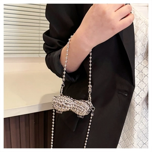 Silver peanut-shaped metal mini bag with bead chain shown on a black blazer outfit