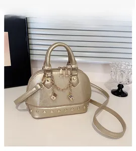 Detail of champagne gold shell bag with metallic chain, dice charms and rivet base trim