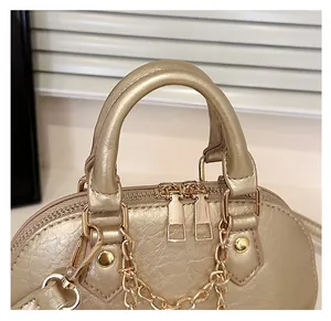 Macro shot of champagne gold textured leather shell bag with handle and dual zippers