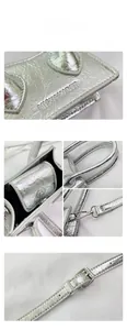 Detail of silver metallic bag showing the pleated texture and magnetic closure buckle
