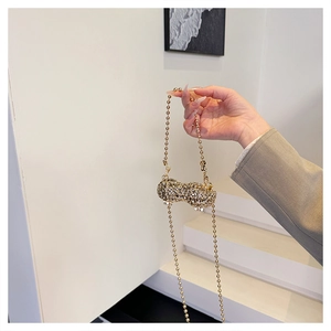 Detailed close-up of a luxury peanut-shaped evening bag with sparkling rhinestones and gold chain