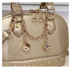 Detail of gold shell bag featuring textured leather, metal studs and dice charm