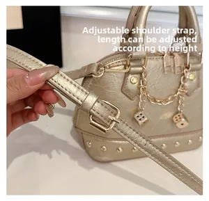 Detail of adjustable PU leather strap with gold buckle and rivet accents on shell bag
