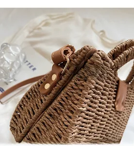 Detail of woven straw bag showing premium gold metal hardware and brown leather trim