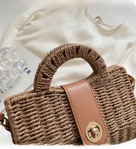 Detailed close-up of handmade straw tote with brown leather flap and golden twist-lock closure