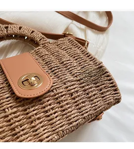 Detail of woven straw handbag featuring a brown faux leather flap and gold twist lock