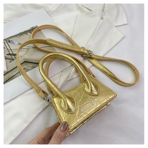 Detailed top view of mini gold metallic crinkle bag on white suit with shoulder strap