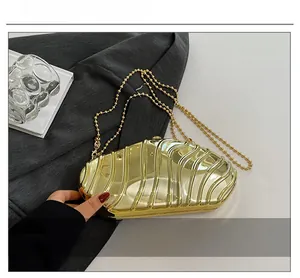 Detail of gold hard-shell evening clutch with irregular rippled texture and beaded chain