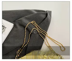 Detailed macro view of golden bead chain strap and wavy acrylic texture on handbag
